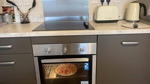 Cozinha com forno embutido, torradeira e chaleira na bancada.
