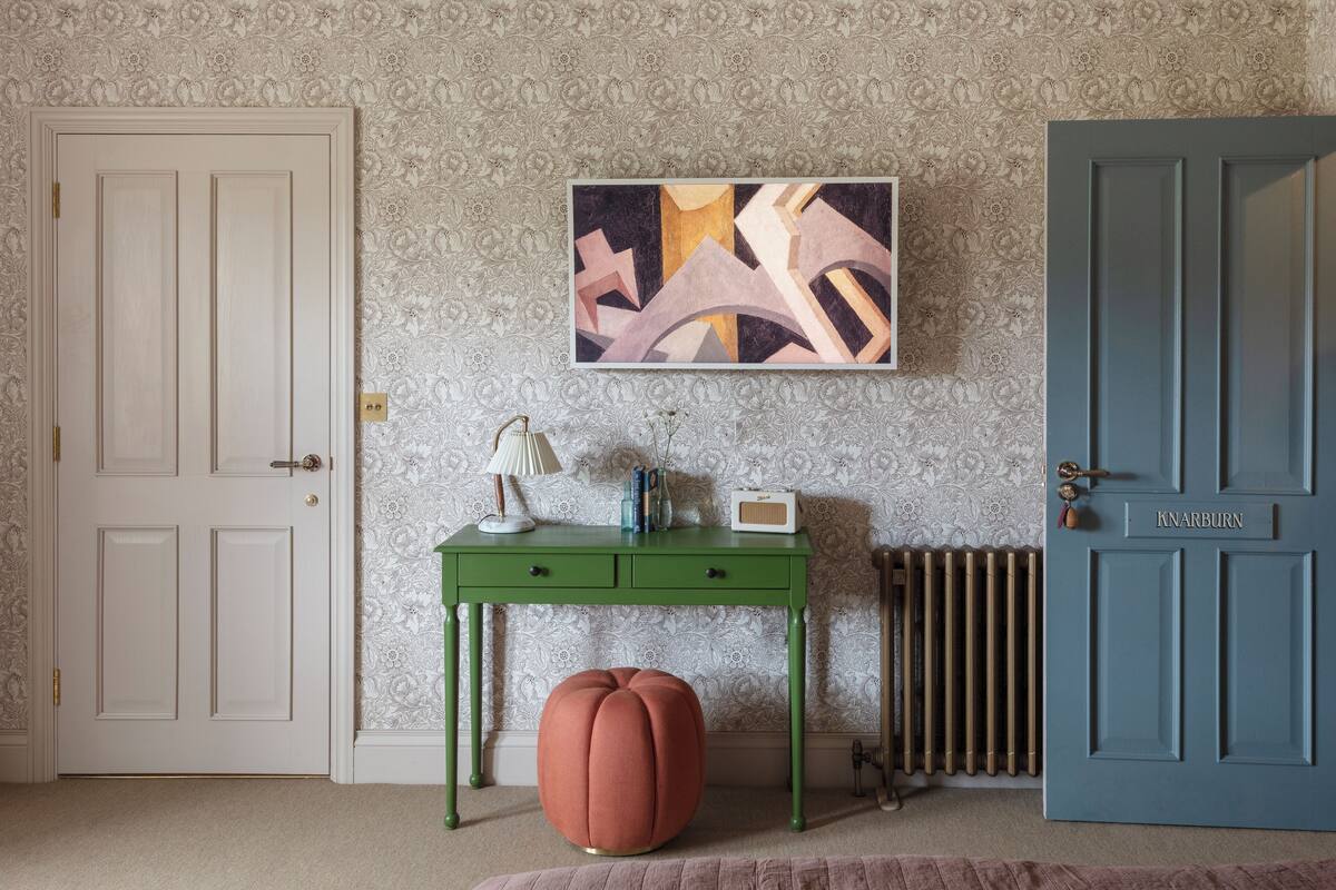 A room with a green desk, a white door, a blue door, and a radiator.
