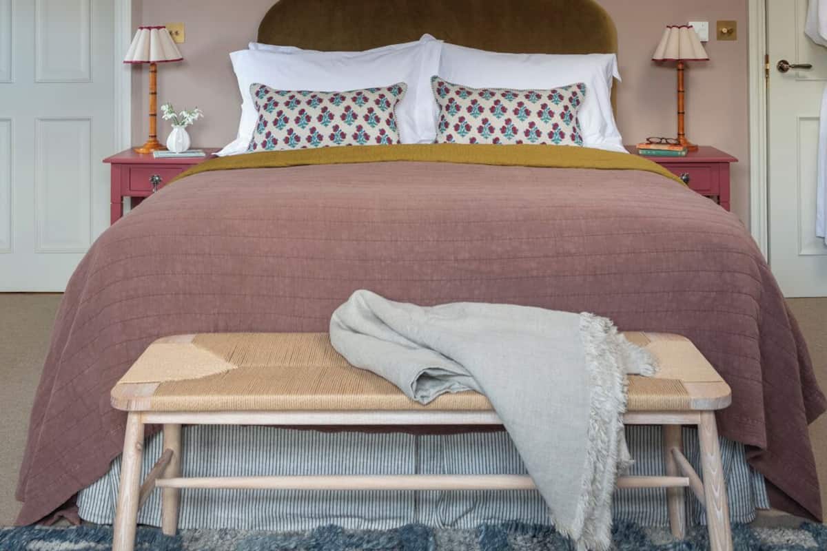 A bedroom with a bed, two bedside tables, a bench, and a patterned rug.