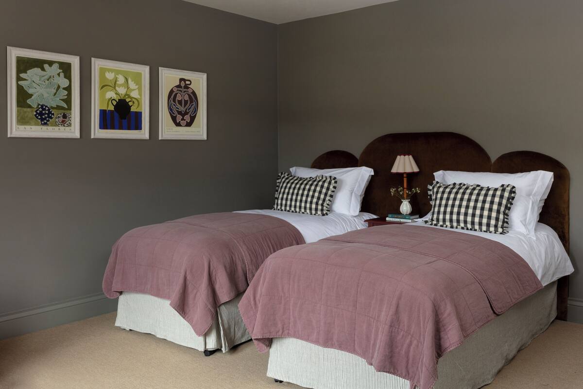 A bedroom with two beds, a nightstand, and three framed artworks on the wall.