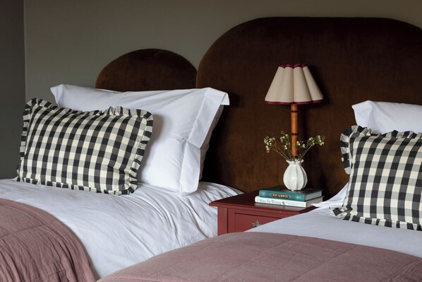A double bed with a checkered pillow, a bedside table with a lamp, and a vase with flowers. - The Kirkstyle Inn & Sportsman's Rest (Brampton)