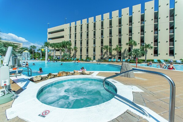Un hotel con piscina, jacuzzi y un edificio con varios balcones.