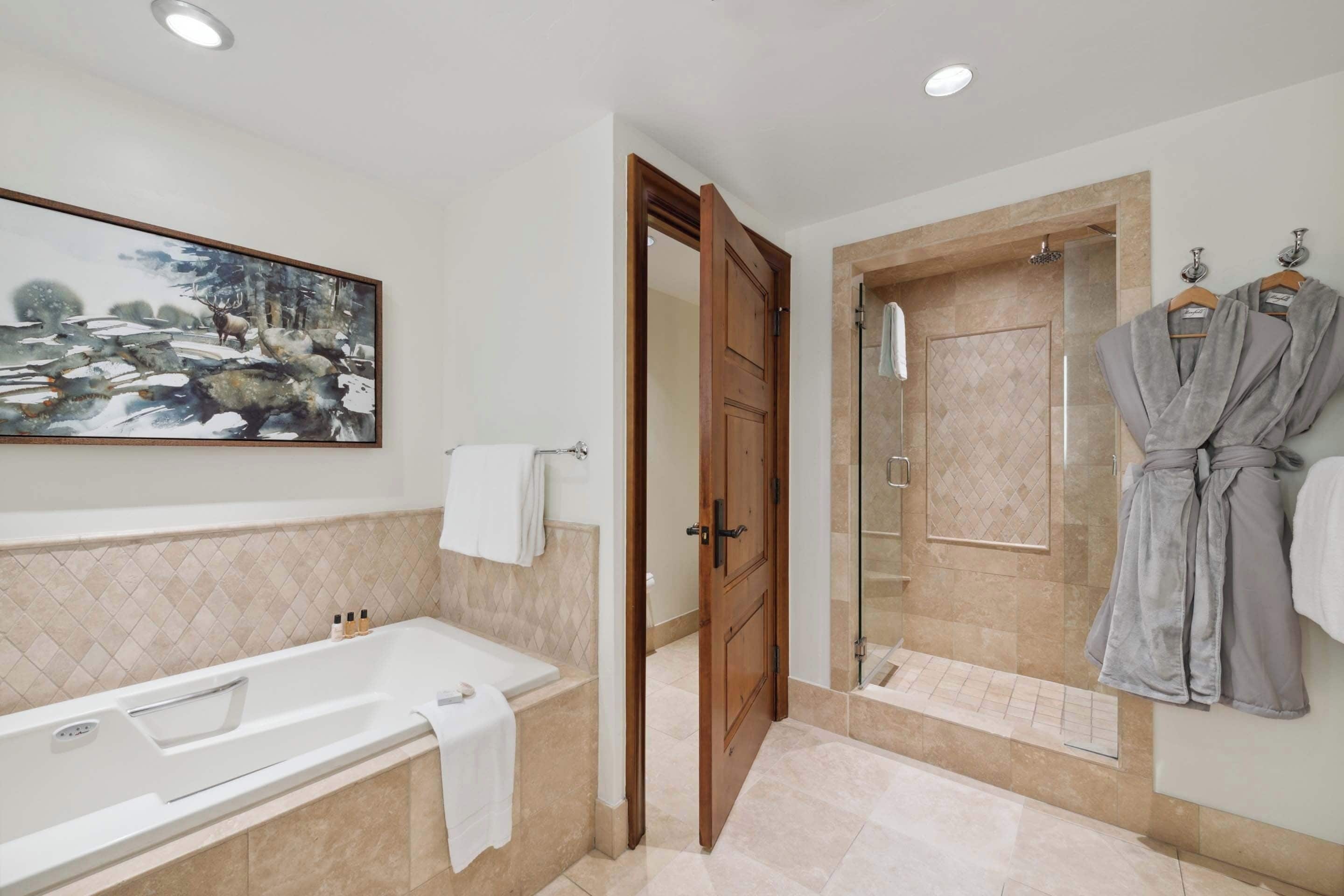 A bathroom with a bathtub, a shower, and a painting on the wall.