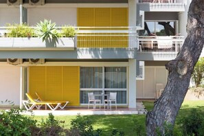 A two-story building with balconies, outdoor seating, and a tree in the foreground. - Apartamentos Turisticos Pinhal Da Marina (Vilamoura)