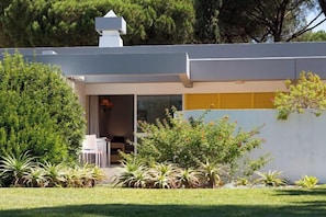 A modern house with a covered patio, surrounded by lush greenery and a well-maintained lawn. - Apartamentos Turisticos Pinhal Da Marina (Vilamoura)