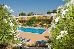 A pool area with lounge chairs and a building in the background. - Apartamentos Turisticos Pinhal Da Marina (Vilamoura)