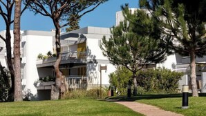 Un bâtiment moderne à la façade blanche, doté d’un balcon apparent et d’un chemin menant à l’entrée.
