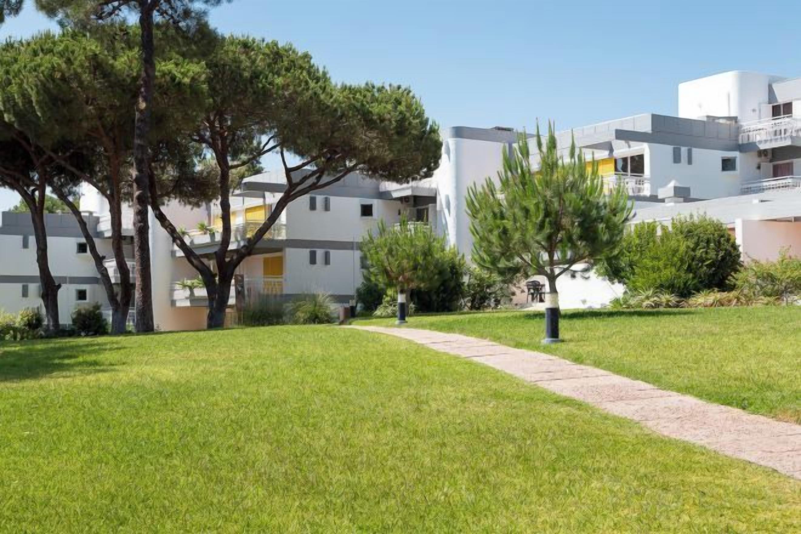 A residential area with modern buildings, a well-maintained lawn, and a pathway.