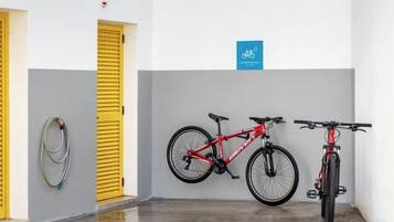 A bicycle storage area with two bicycles, a yellow door, and a blue sign indicating a bike-friendly facility.