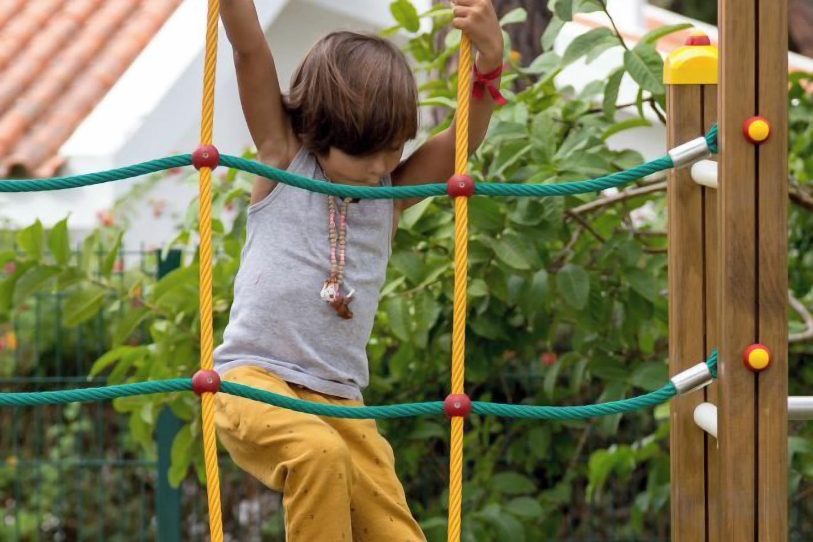 A child climbing a rope ladder structure outdoors.