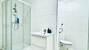 A modern bathroom with a glass shower enclosure, a white vanity with a sink, and a toilet.
