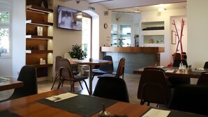 Un café moderno con muebles de madera, un televisor montado en la pared y una barra con diversos artículos.