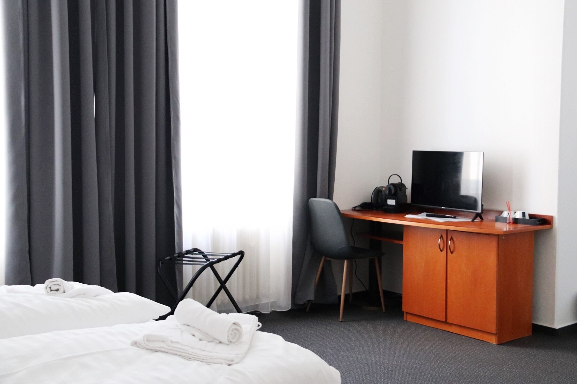 Une chambre d’hôtel avec un lit, un bureau avec une télévision, une chaise et une petite table.