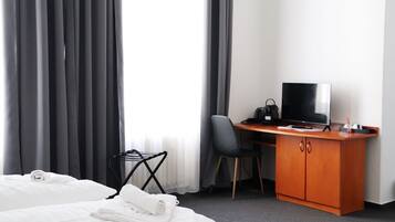 Une chambre d’hôtel avec un lit, un bureau avec une télévision, une chaise et une petite table.