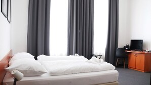Una habitación de hotel con una cama, un escritorio con televisor y una silla.