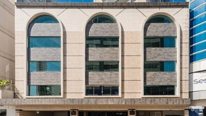 A building with three arched windows, a flat facade, and a sign with the letters 'Se' visible.