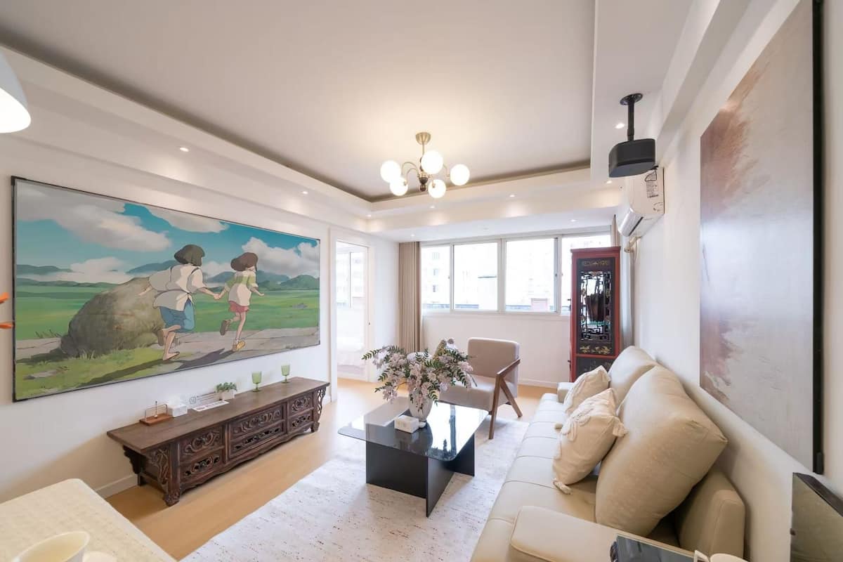 A spacious living room with a large painting, a sofa, a coffee table, and a cabinet.