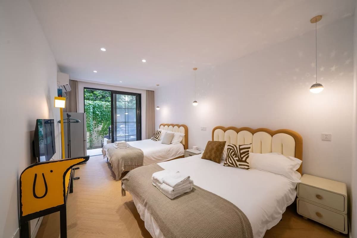A hotel room with two beds, a TV, a desk, and a chair.