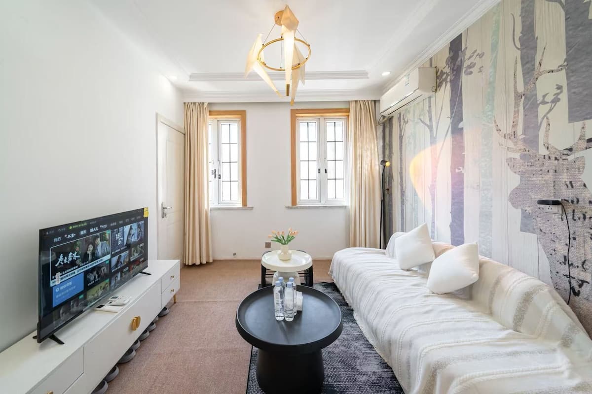 A modern living room with a flat-screen TV, a sofa, a coffee table, and a decorative wall.