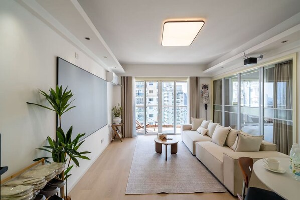 A modern living room with a sofa, a coffee table, and a large window.