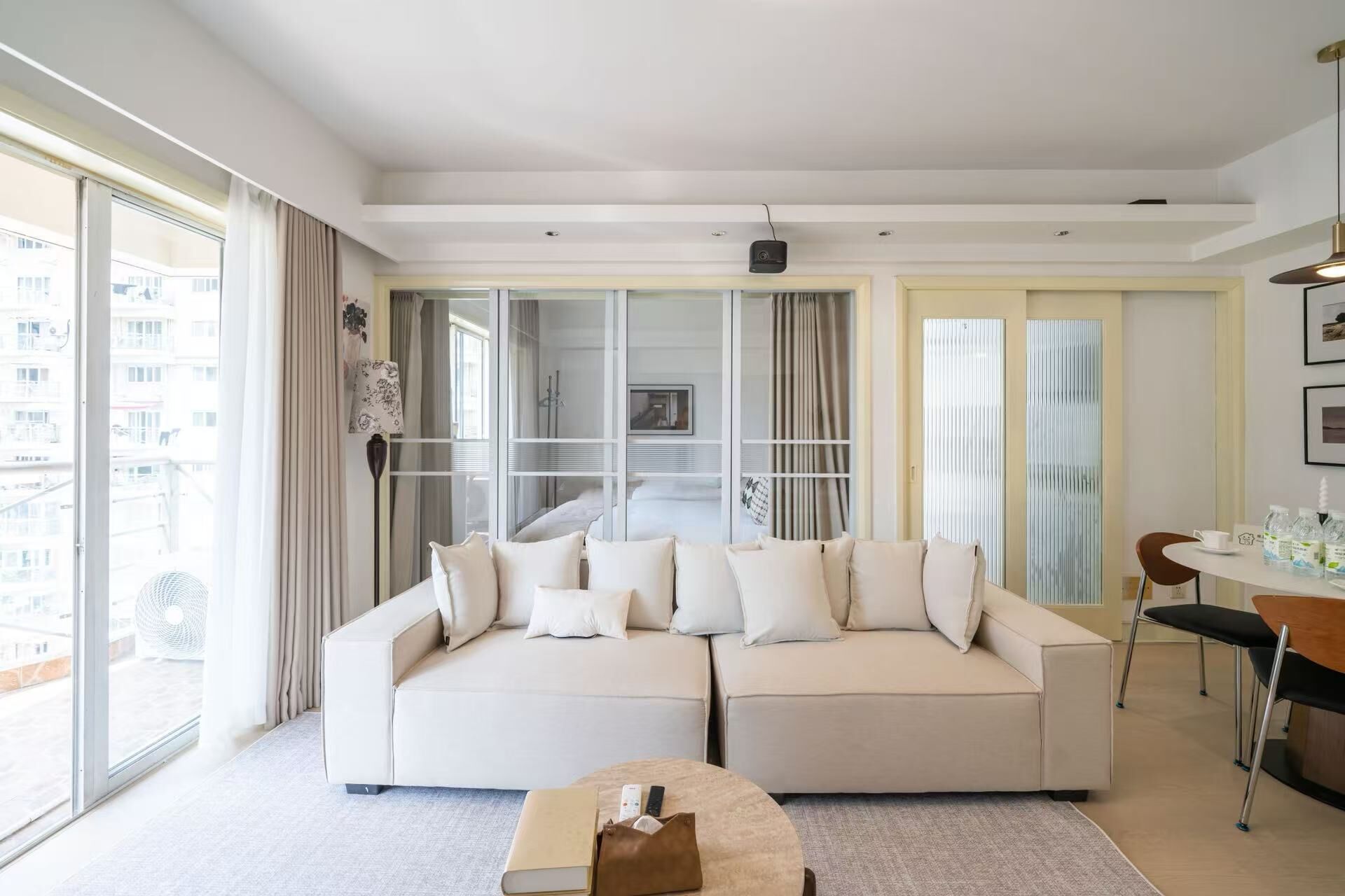 A modern living room with a large sofa, a coffee table, and a dining area with chairs.