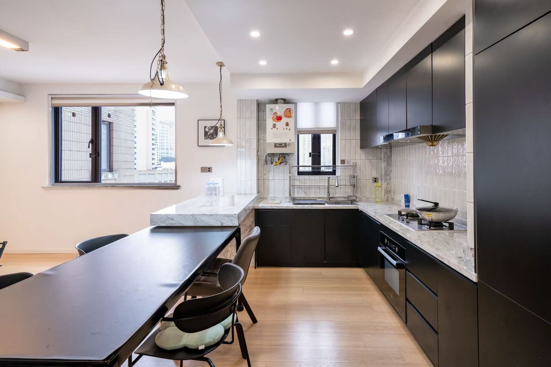 A modern kitchen with a marble countertop, black cabinets, and a dining area with a table and chairs.