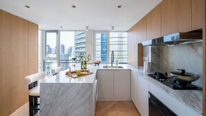 A modern kitchen with a marble island, wooden cabinets, and a city view. - Book and Bed-People's Square (Shanghai)