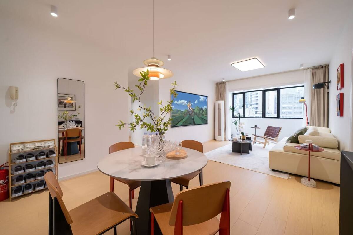 A modern living room with a dining area, a sofa, a coffee table, and a large window.