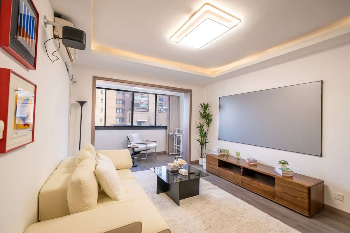 A living room with a sofa, coffee table, TV, and a plant.