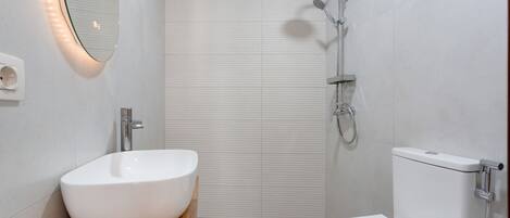 A modern bathroom with a white sink, a toilet, and a shower.
