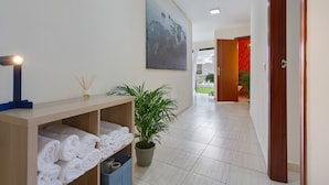 A hallway with a wooden bench, a potted plant, and a wall-mounted artwork. - Luxury Penthouse Plaza Apartment with Mountain View, Private Terrace, and Wi-Fi (Playa San Juan)