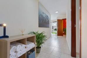 A hallway with a wooden bench, a potted plant, and a wall-mounted artwork.