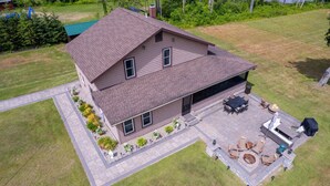 A two-story house with a patio area featuring outdoor furniture and a fire pit.