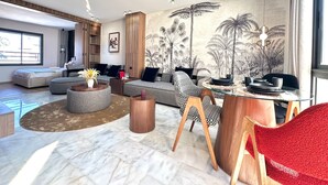 Una sala de estar moderna con un sofá grande, una mesa de centro de vidrio y un comedor con una silla roja.