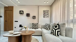 Una sala de estar moderna con un sofá modular, una mesa de centro de madera redonda y una decoración de estilo minimalista.