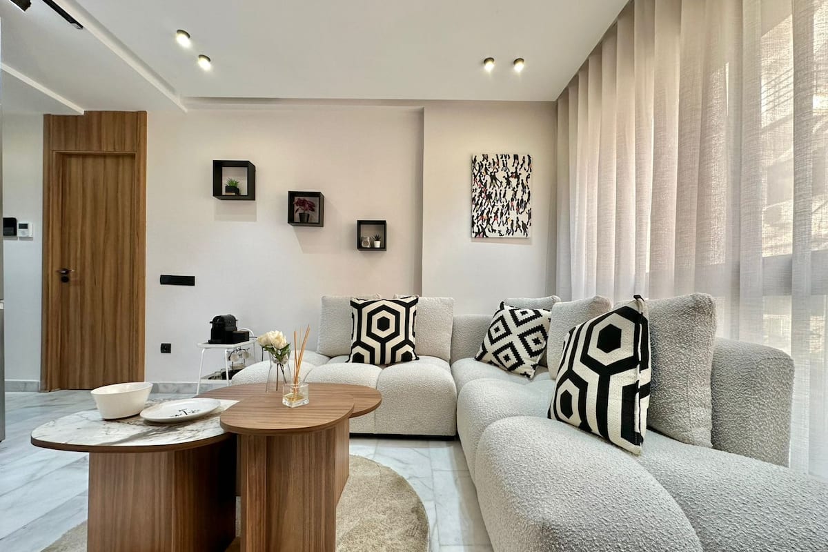 A modern living room with a sectional sofa, a round wooden coffee table, and a minimalist decor style.