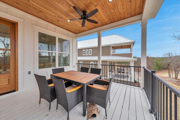 Une terrasse extérieure avec un plafond en bois, une table et des chaises, et une vue sur une maison.