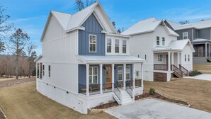 Ein zweistöckiges Haus mit überdachter Veranda und kleinem Vorgarten.