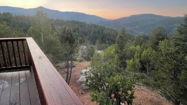Una terraza de madera con vistas a una cadena montañosa boscosa.