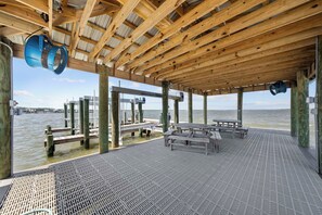Una terraza cubierta de madera con barandillas metálicas, bancos y vista al agua.