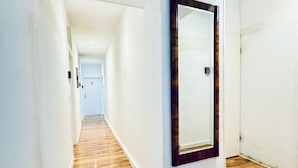 Un couloir doté d’un plancher en bois, de murs blancs et d’une porte avec un cadre en bois.