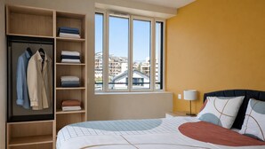 A hotel room with a bed, a wardrobe, and a window with a view of buildings. - Le Nouveau Rivage (T2 lake view) (Aix-les-Bains)