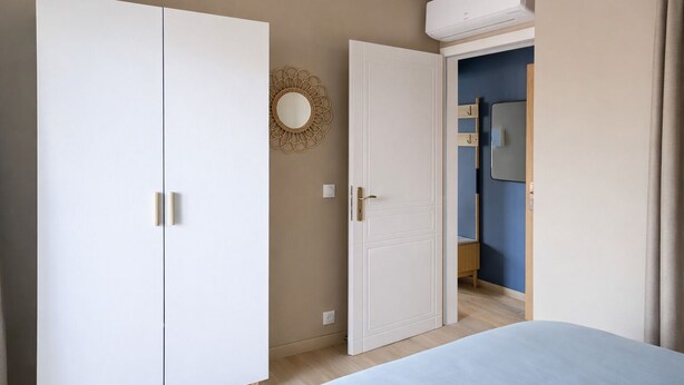 A bedroom with a bed, a wardrobe, and a bathroom visible through an open door. - L'Ecume des Ondes (T2 mountain view) (Aix-les-Bains)