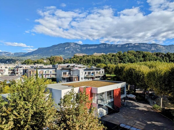 Una zona residencial moderna con edificios contemporáneos, un estacionamiento y montañas al fondo.