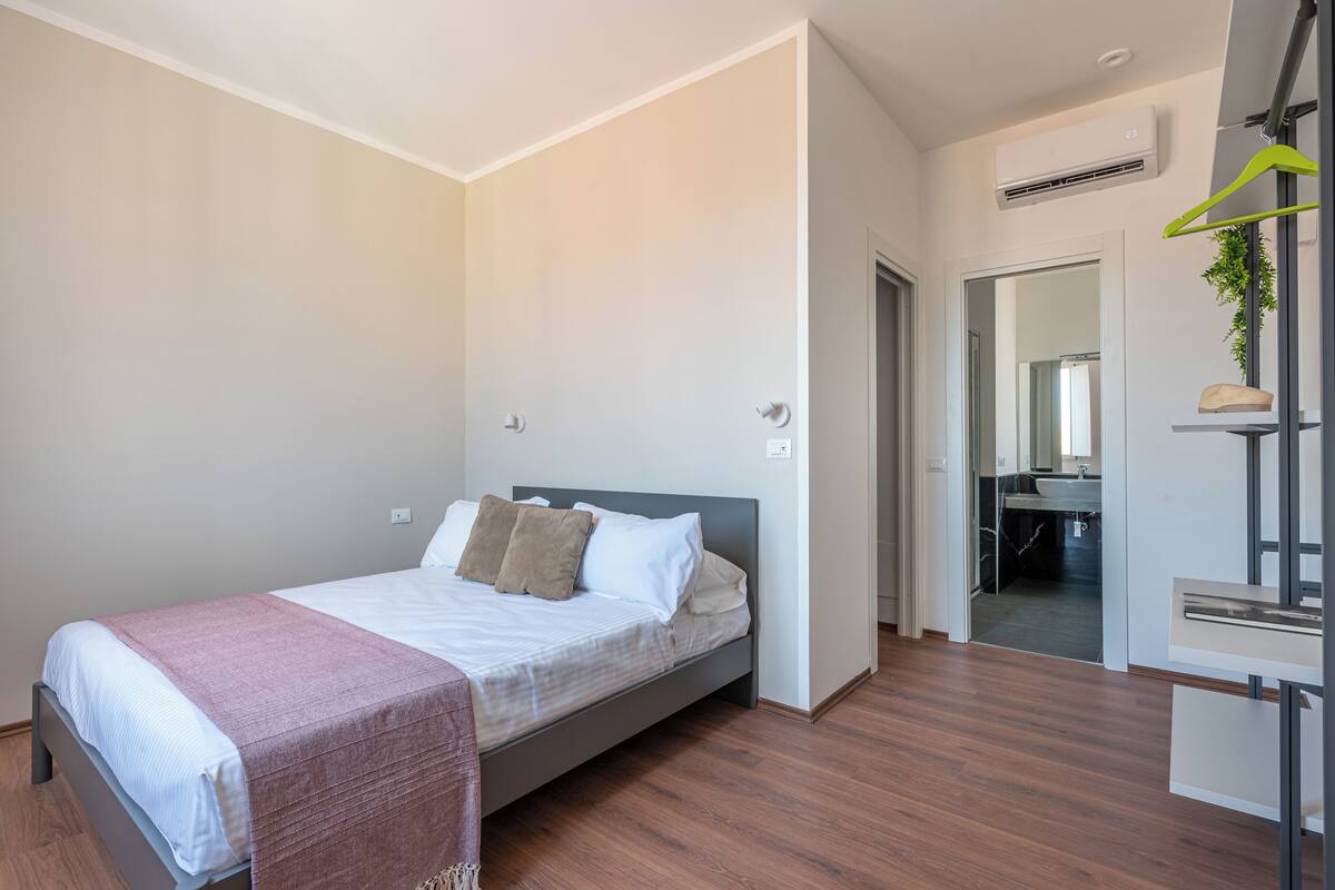 Camera da letto moderna con un letto, un comodino e uno specchio.
