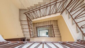 Una scala con ringhiera in metallo, gradini in marmo e una parete gialla.