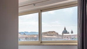 Una finestra che offre vista su un paesaggio urbano, con un edificio a cupola particolarmente evidente.