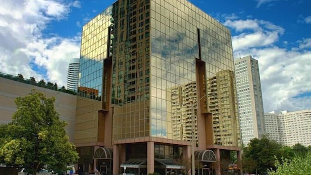 A modern glass building with a grid-like facade, surrounded by other high-rise structures. - Rook Hotel   (Mississauga)