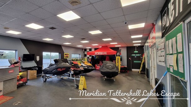 A boat rental facility with jet skis, a covered area, and a sign for 'Meridian Tattersall Lakes Escape'.