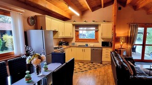 Una cocina acogedora con vigas de madera, un comedor con piso a cuadros y una sala de estar con televisor y candelabro.